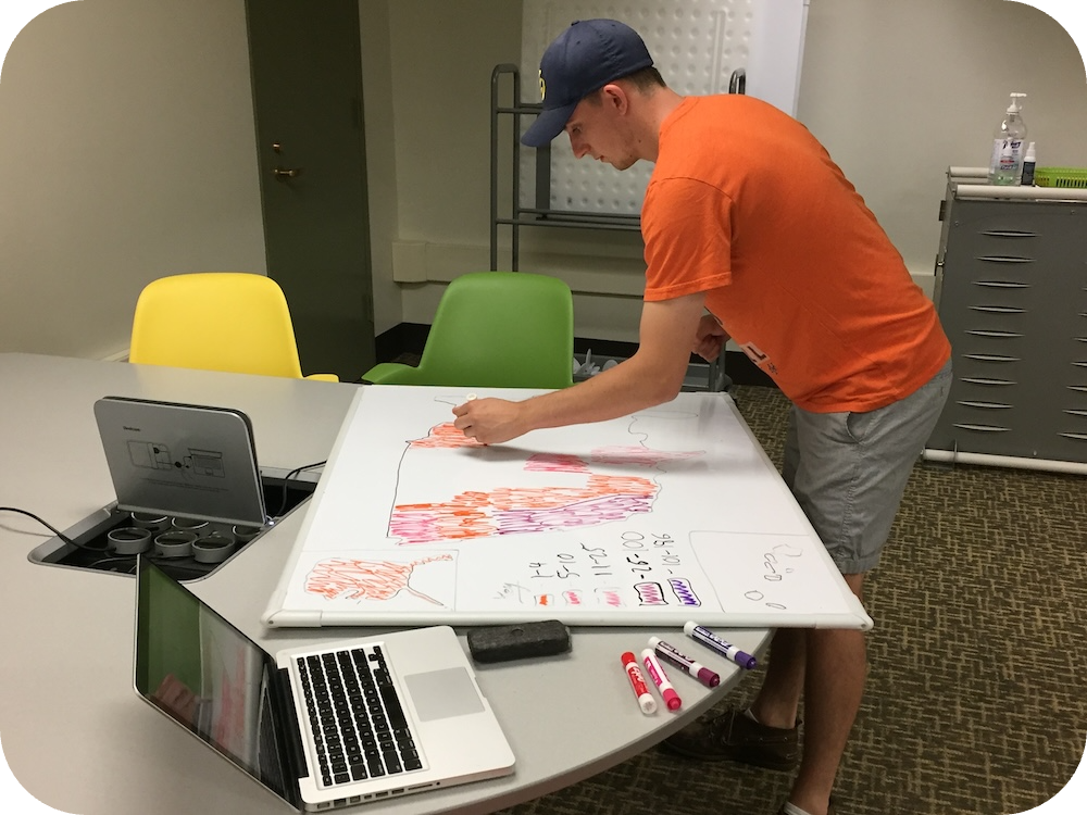 Rennie Heza draws a data visualization on a white board